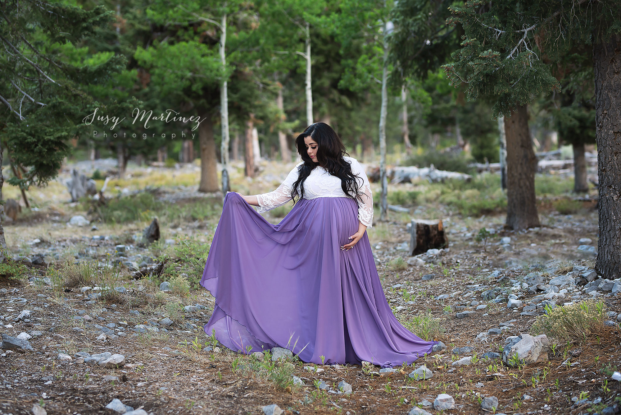mom twirls purple dress during mountain maternity portraits