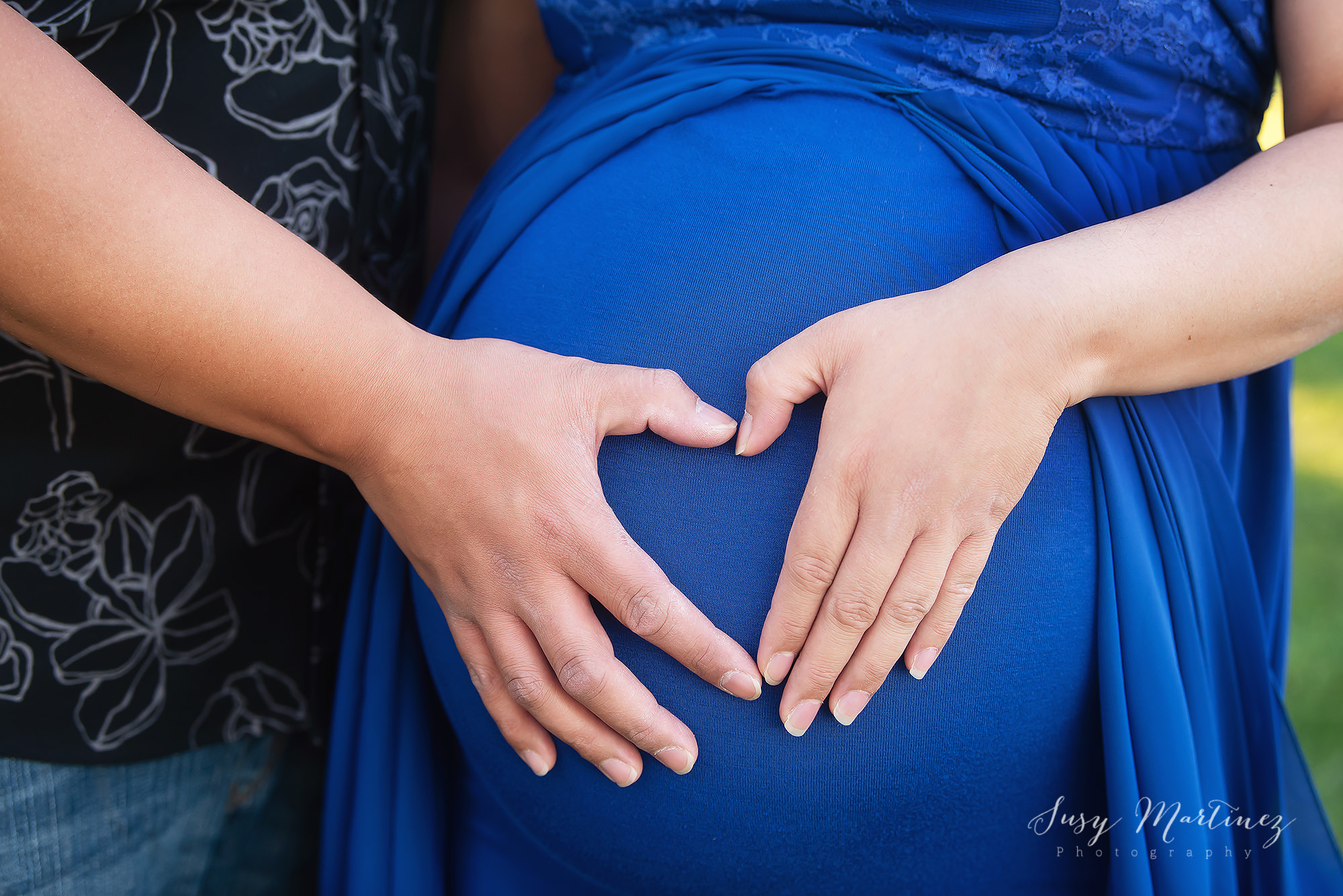 expectant parents make heart with hands on mom's belly