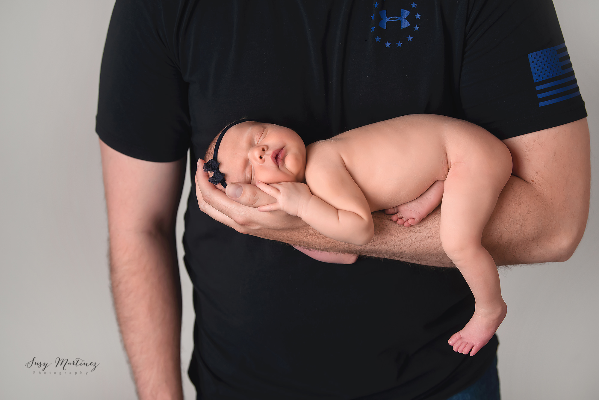 dad holds newborn baby girl on arm in Las Vegas studio