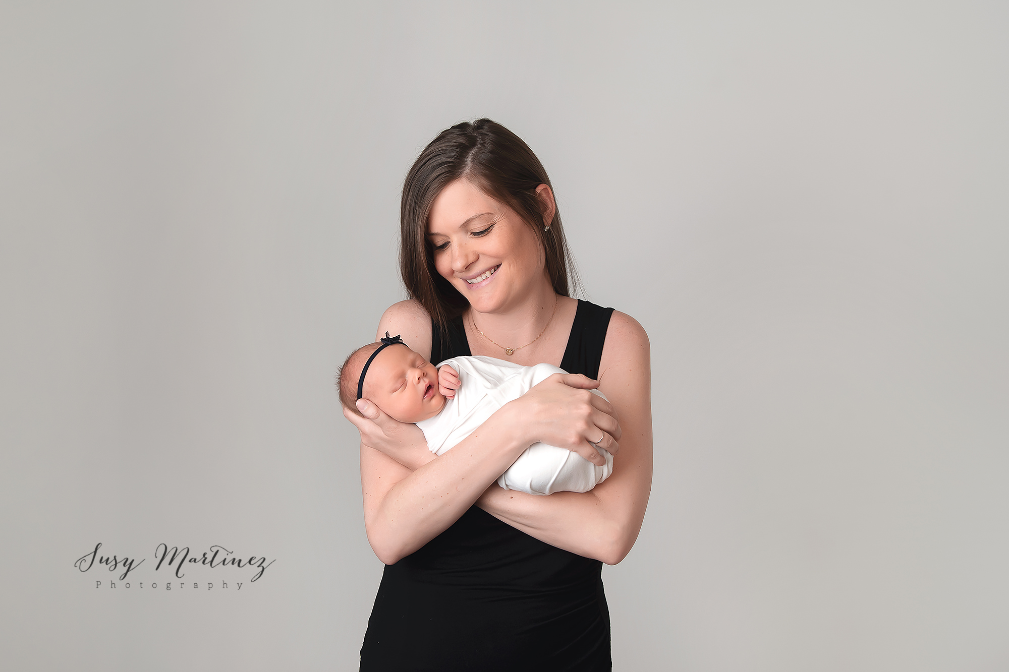 mom holds newborn baby girl during Pastel Newborn Mini Session