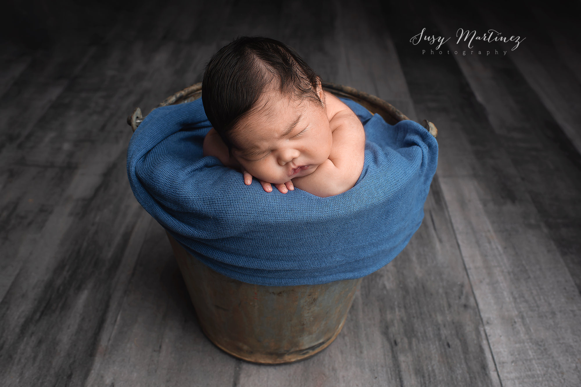 Henderson Newborn Photographer photographs baby boy in bucket with blue blanket