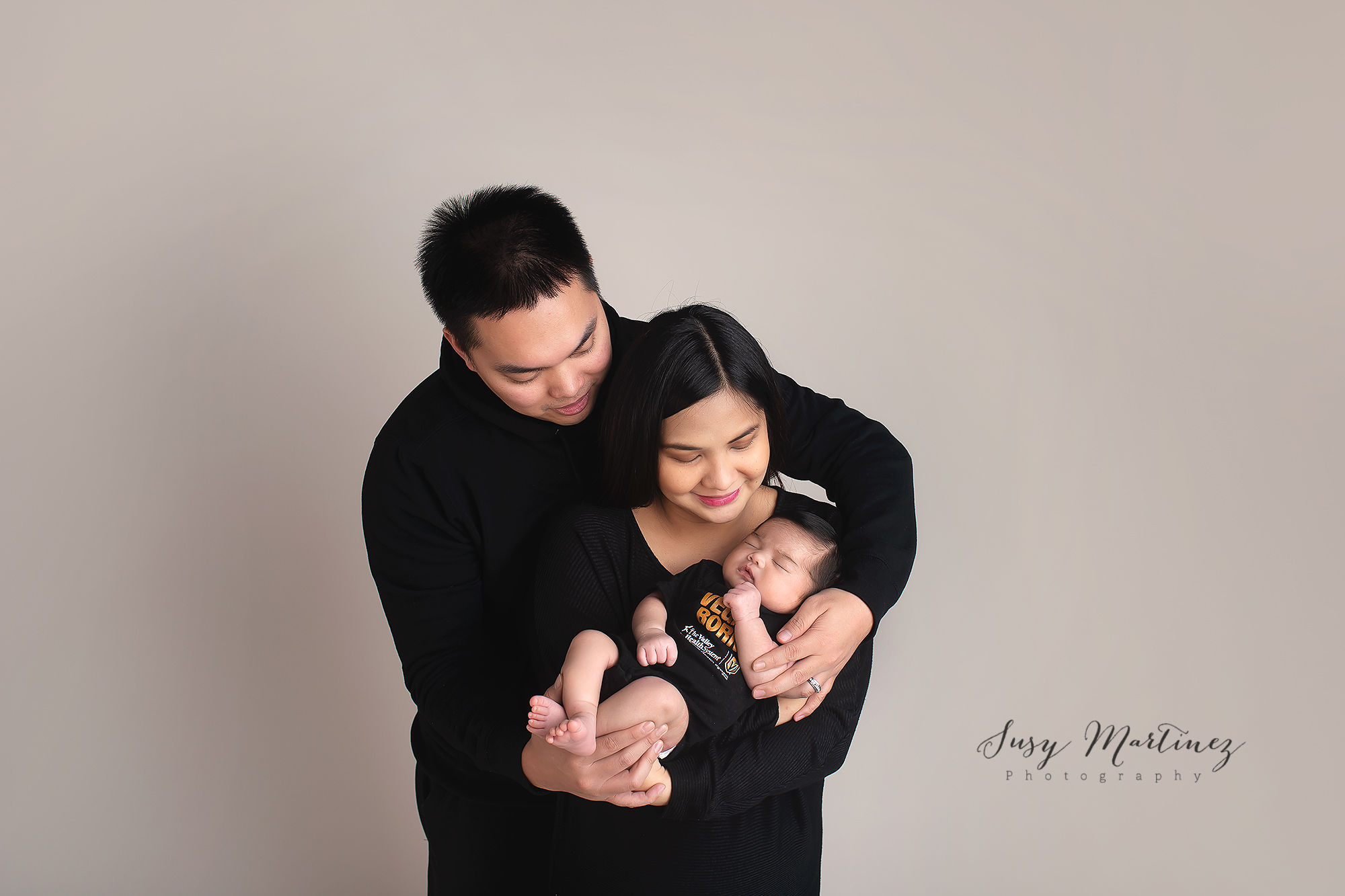 family holds newborn and smiles during Studio Newborn Portraits in Las Vegas