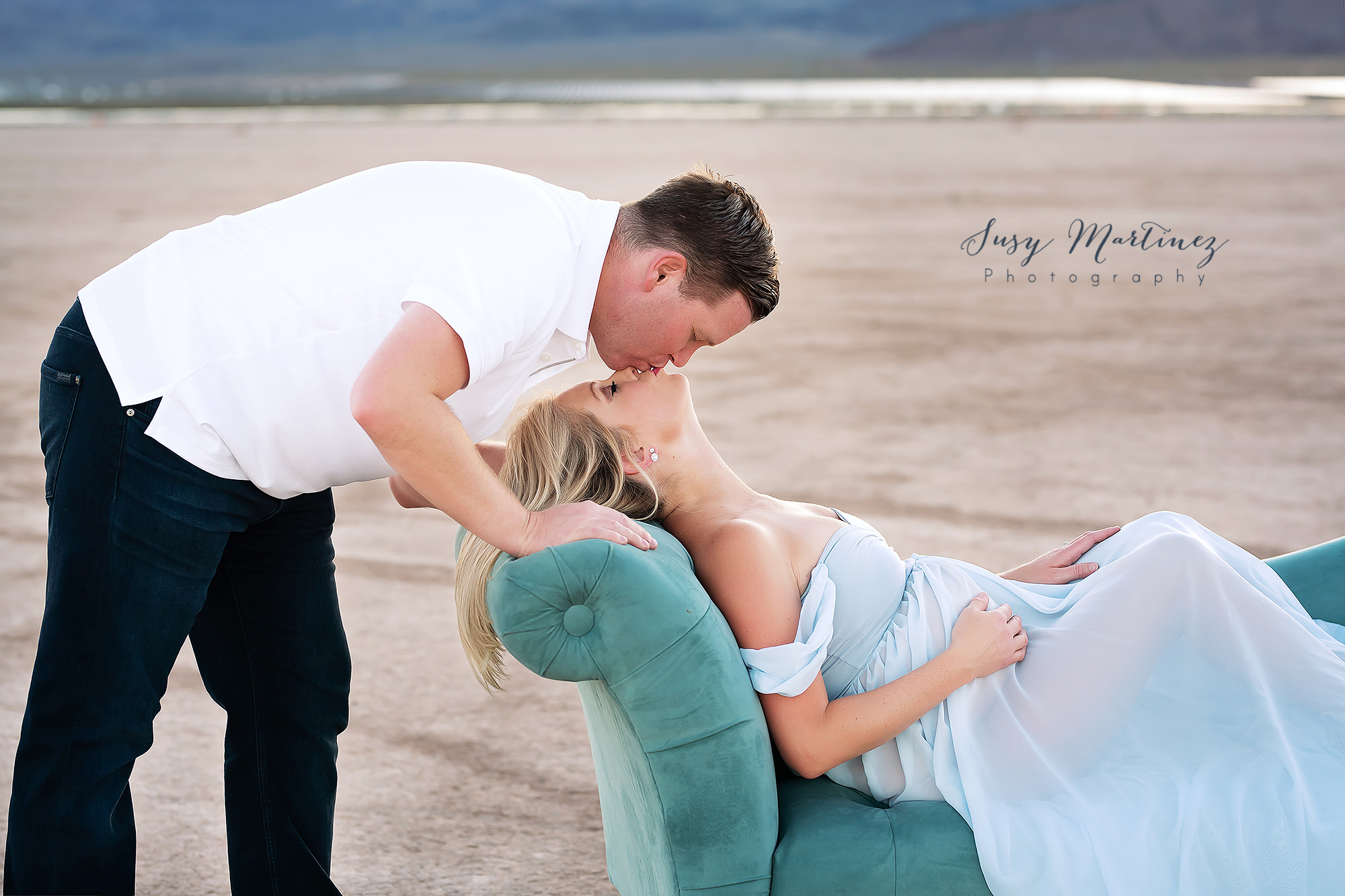 mom leans head back on sofa arm kissing dad during maternity session