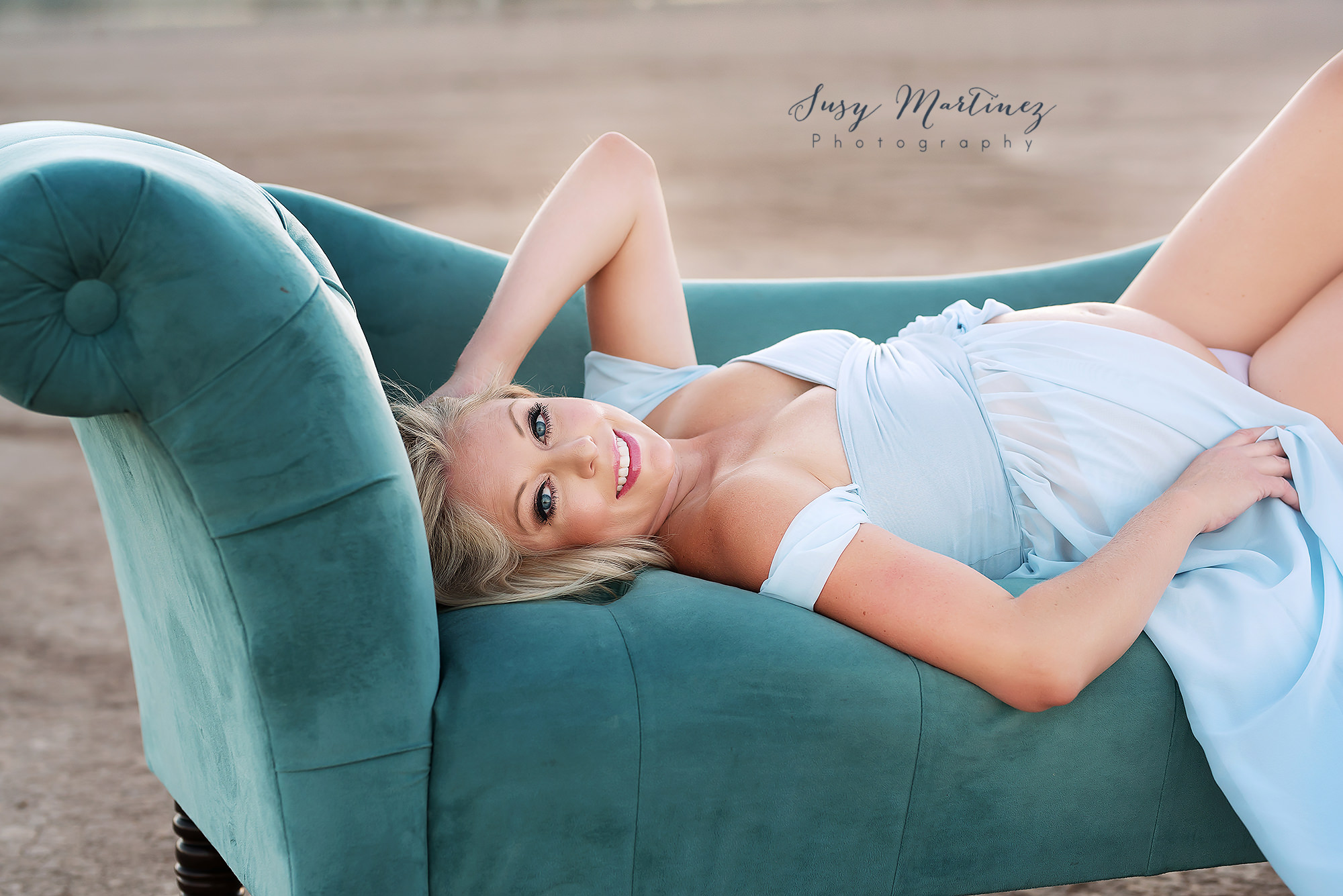 mom lays on teal couch during maternity session in Las Vegas
