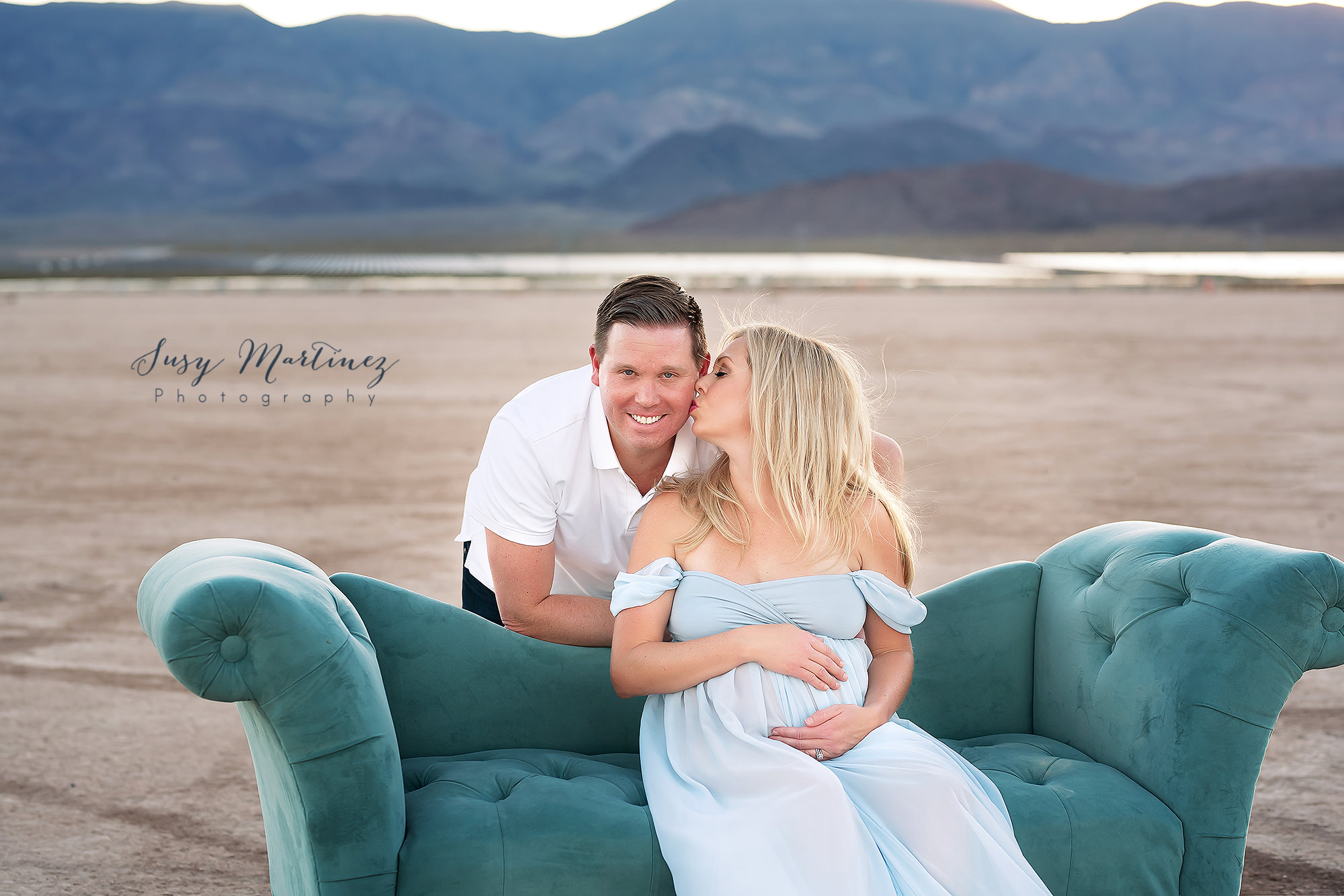 parents pose on teal couch during Dry Lake Bed maternity session