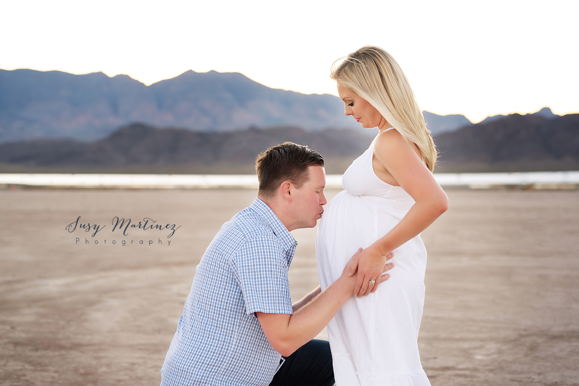 dad-to-be kisses baby in mom's belly during Dry Lake Bed maternity session
