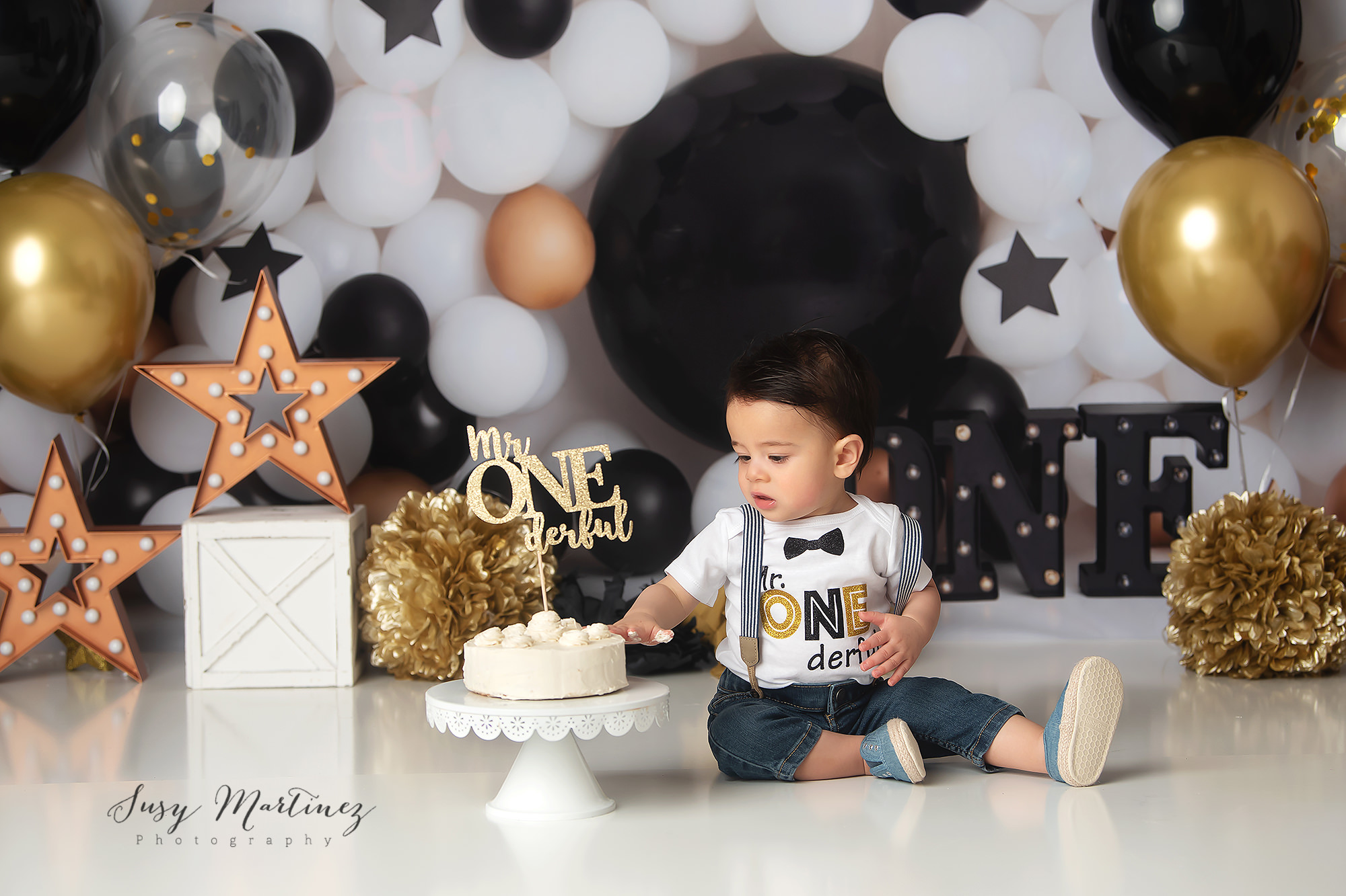 first birthday cake smash for baby boy with gold, black, and ivory balloons