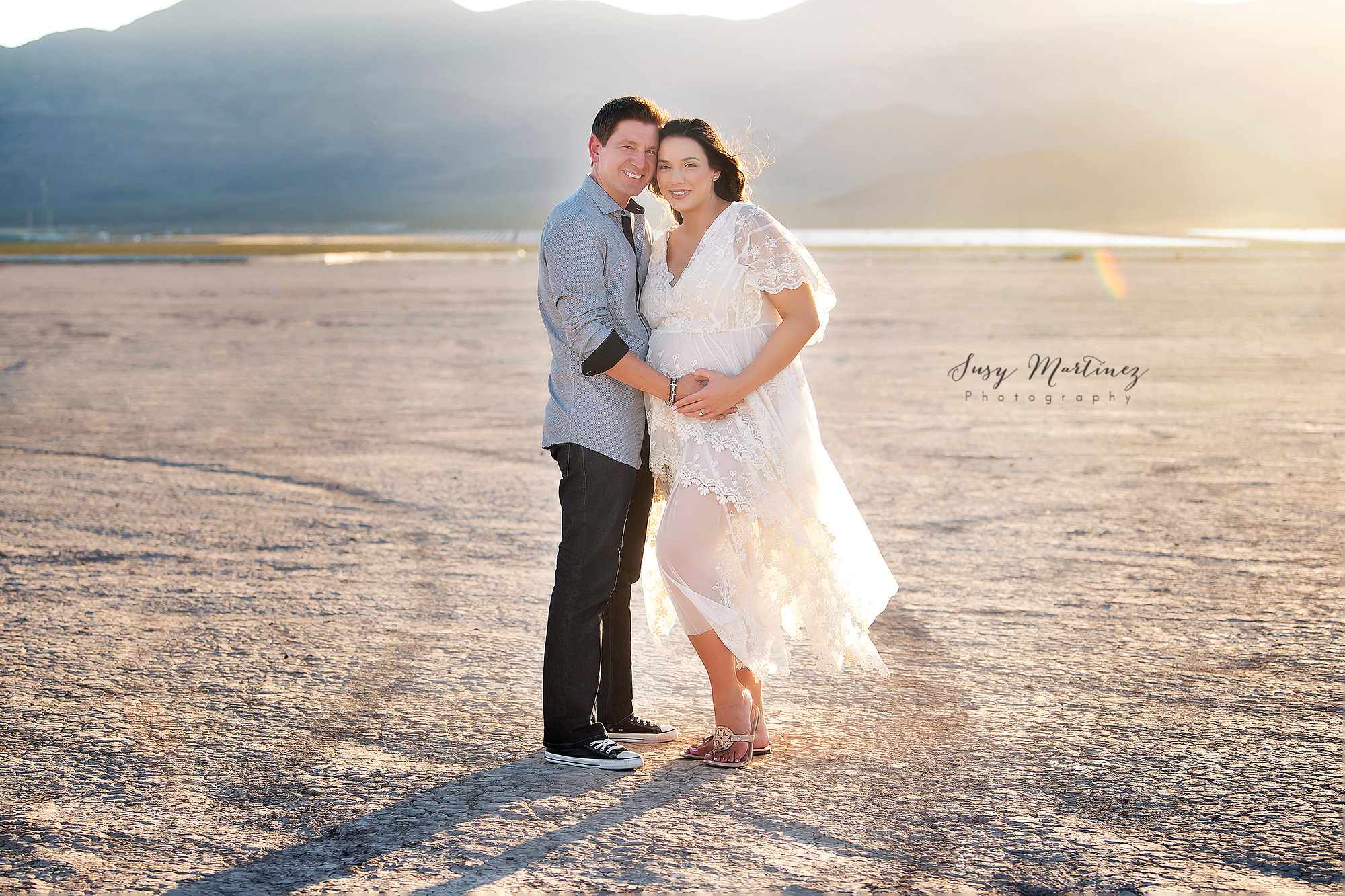 couple expecting baby poses in Dry Lake bed