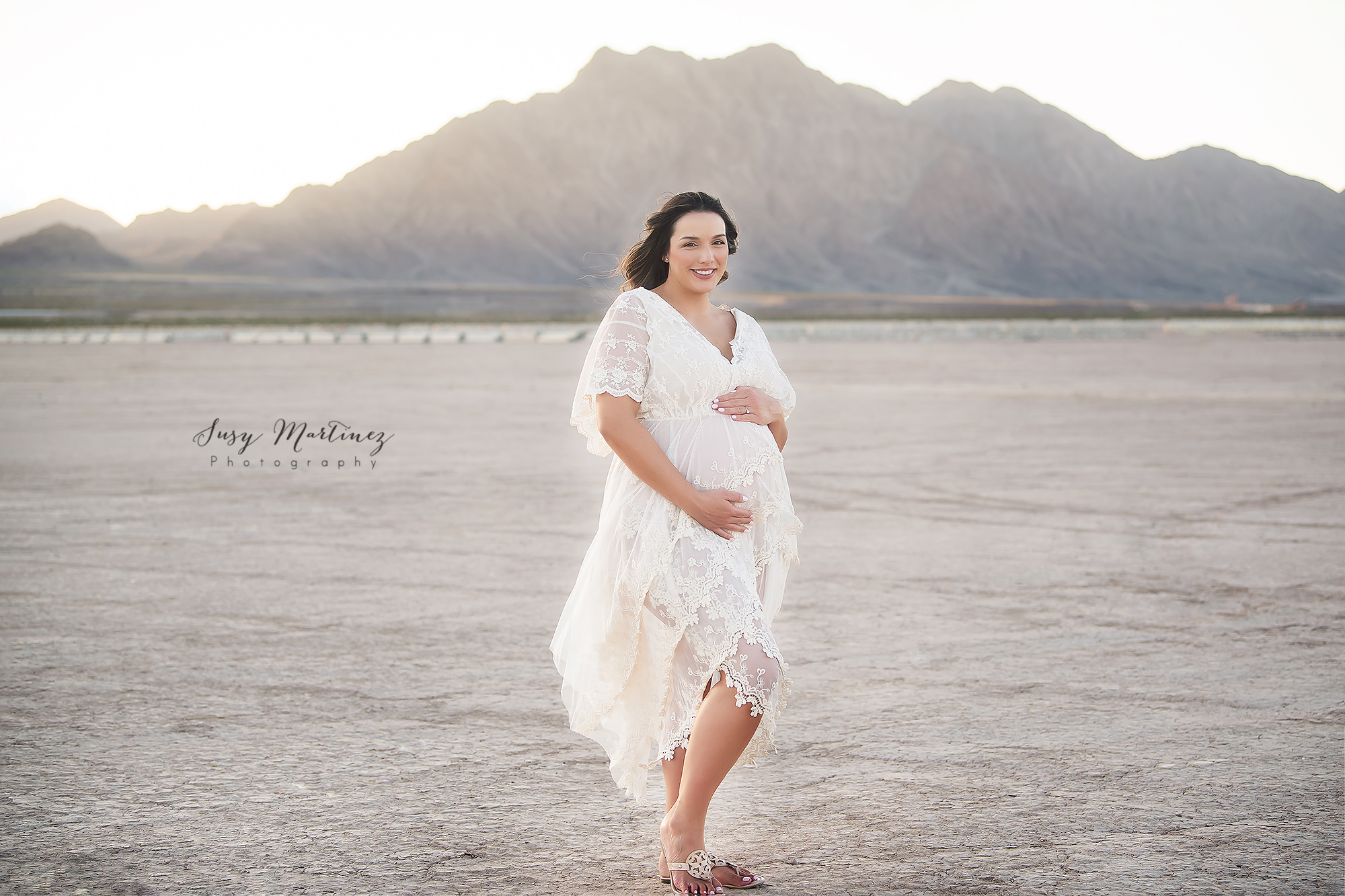 mom poses in boho maternity dress in Dry Lake Bed
