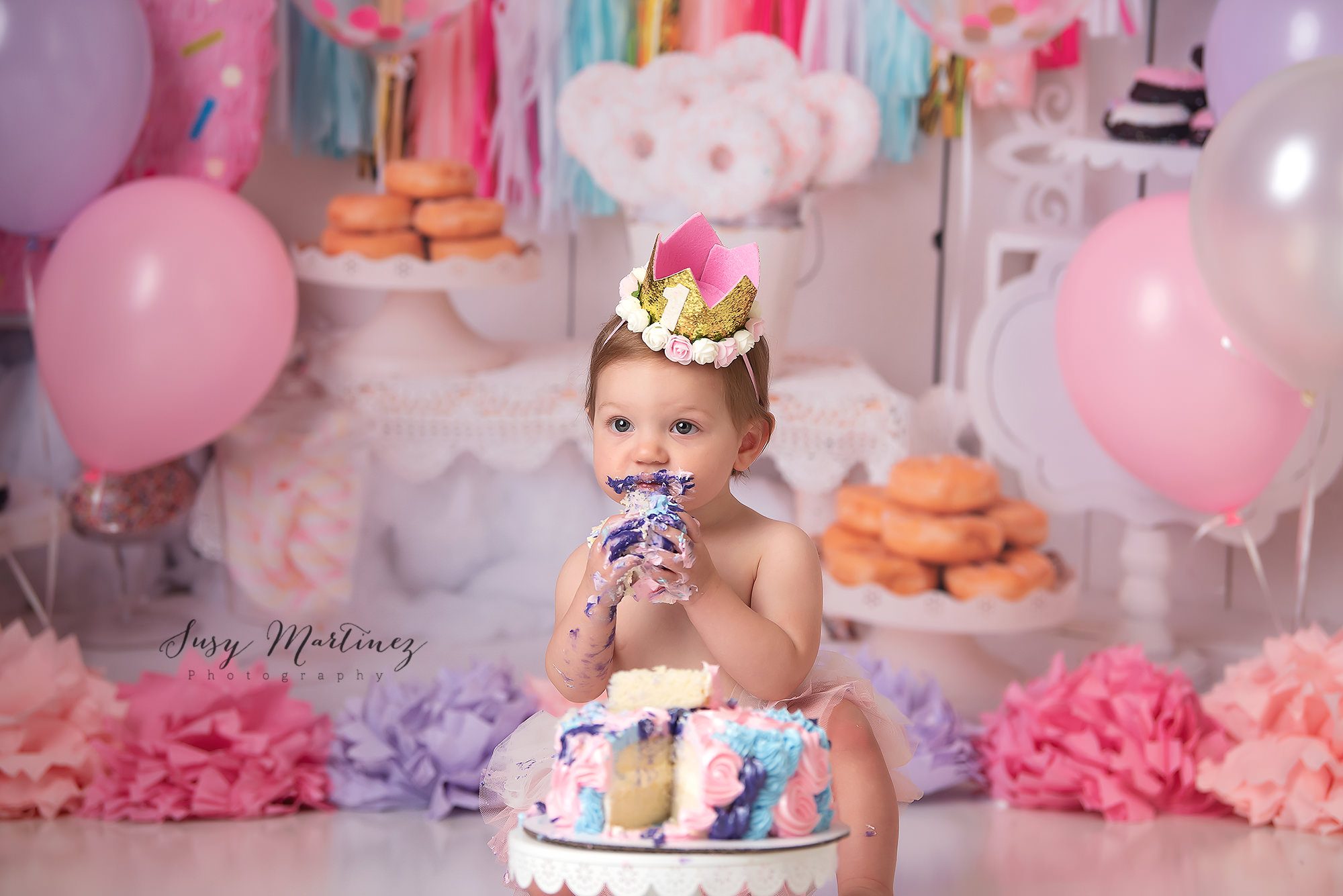 baby eats cake with purple icing during pastel cake smash