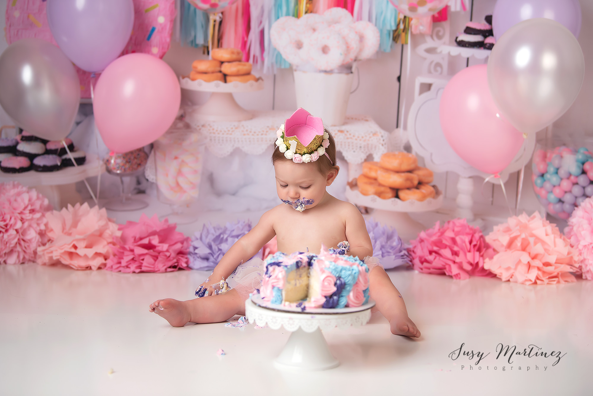 baby girl eats pink and blue cake during pastel cake smash
