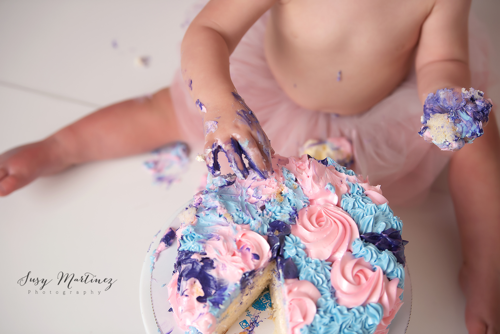 toddler plays with icing during pastel cake smash