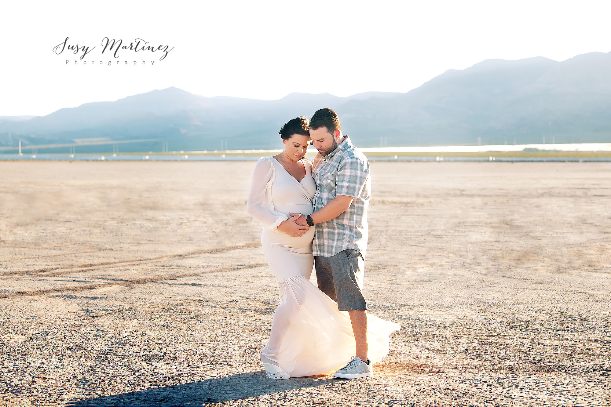 mom and dad look down at belly during Dry Lake Bed Maternity Photos