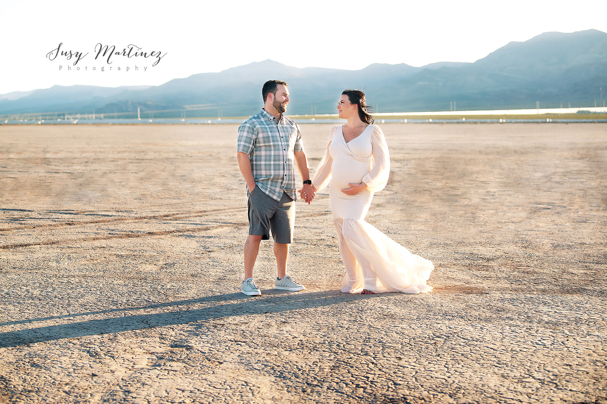 expecting parents hold hands during Dry Lake Bed Maternity Photos
