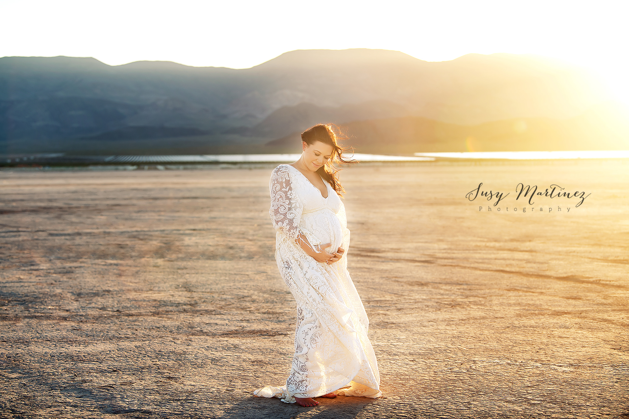 mom in boho maternity gown poses in Dry Lake Bed