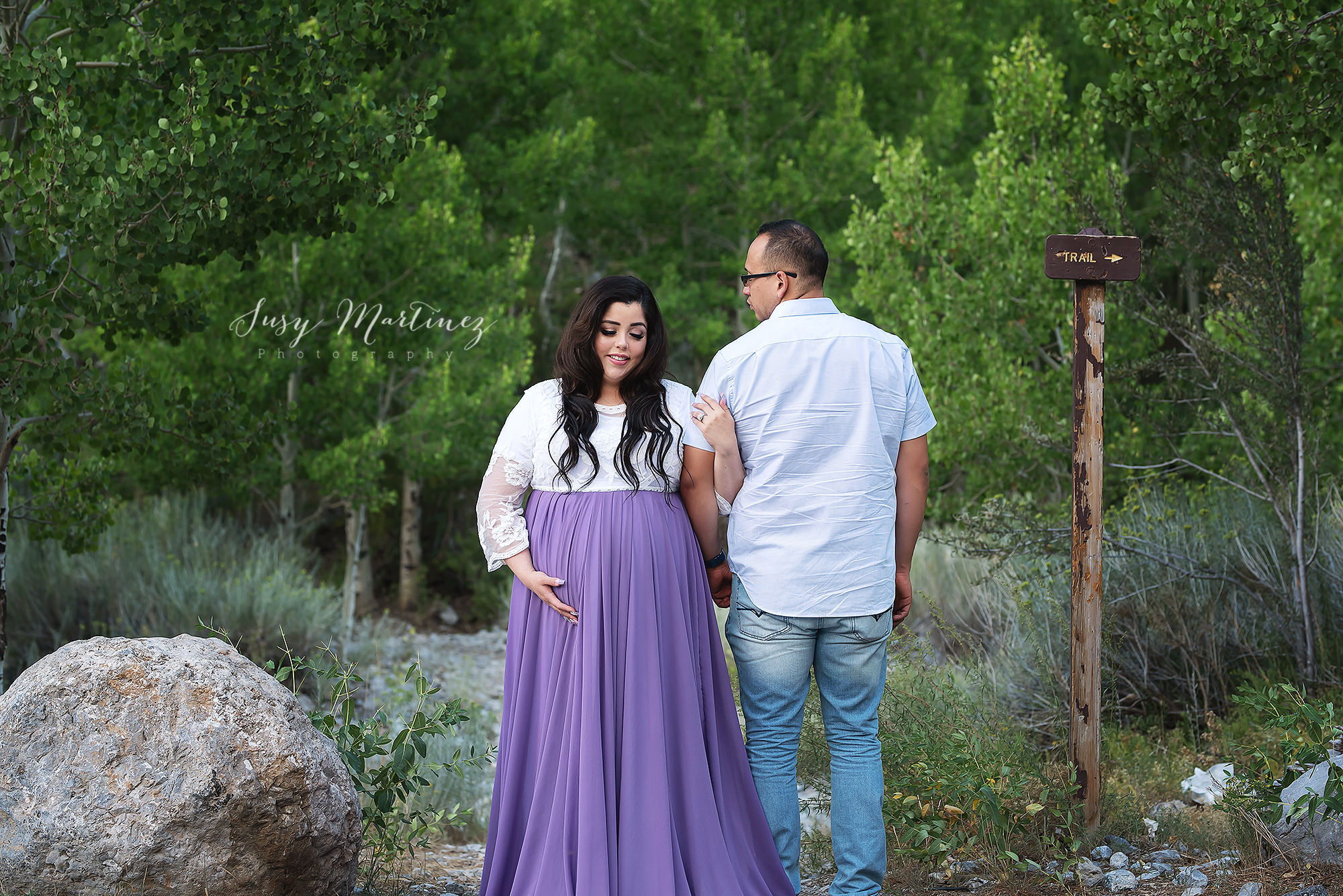 mom and dad pose on mountain trail with Susy Martinez Photography for maternity session