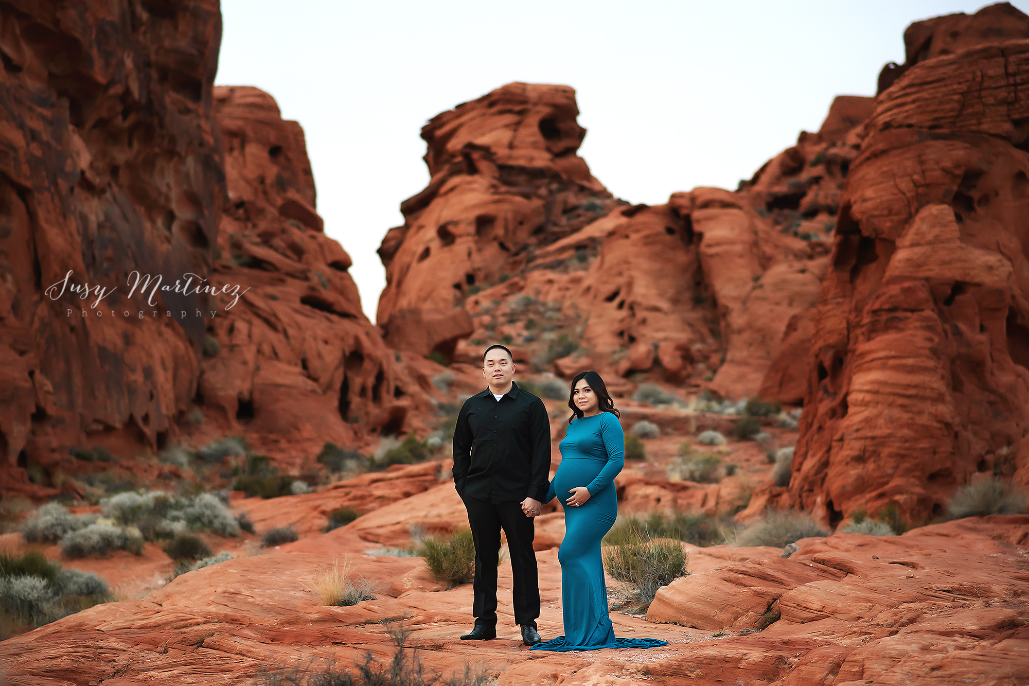 parents hold hands standing in Valley of Fire during maternity session