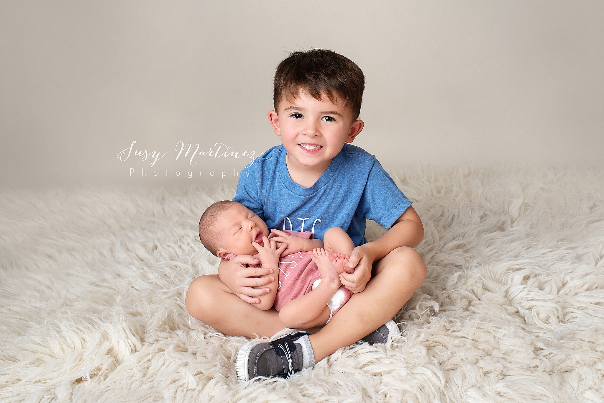 big brother holds newborn sister during studio newborn portraits