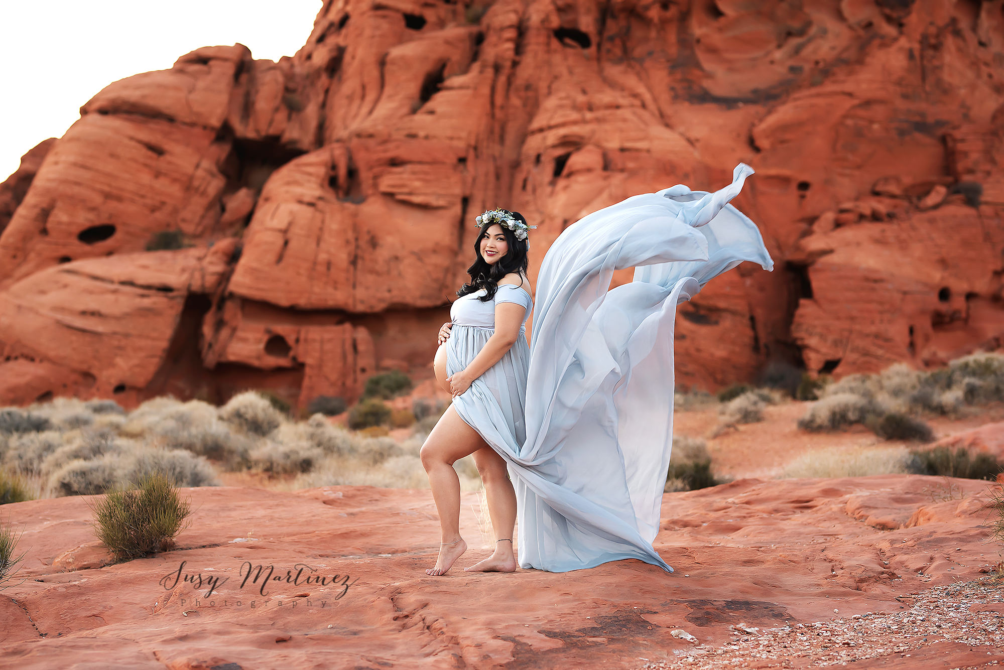 light blue gown floats behind mom holding belly during Valley of Fire Maternity Session