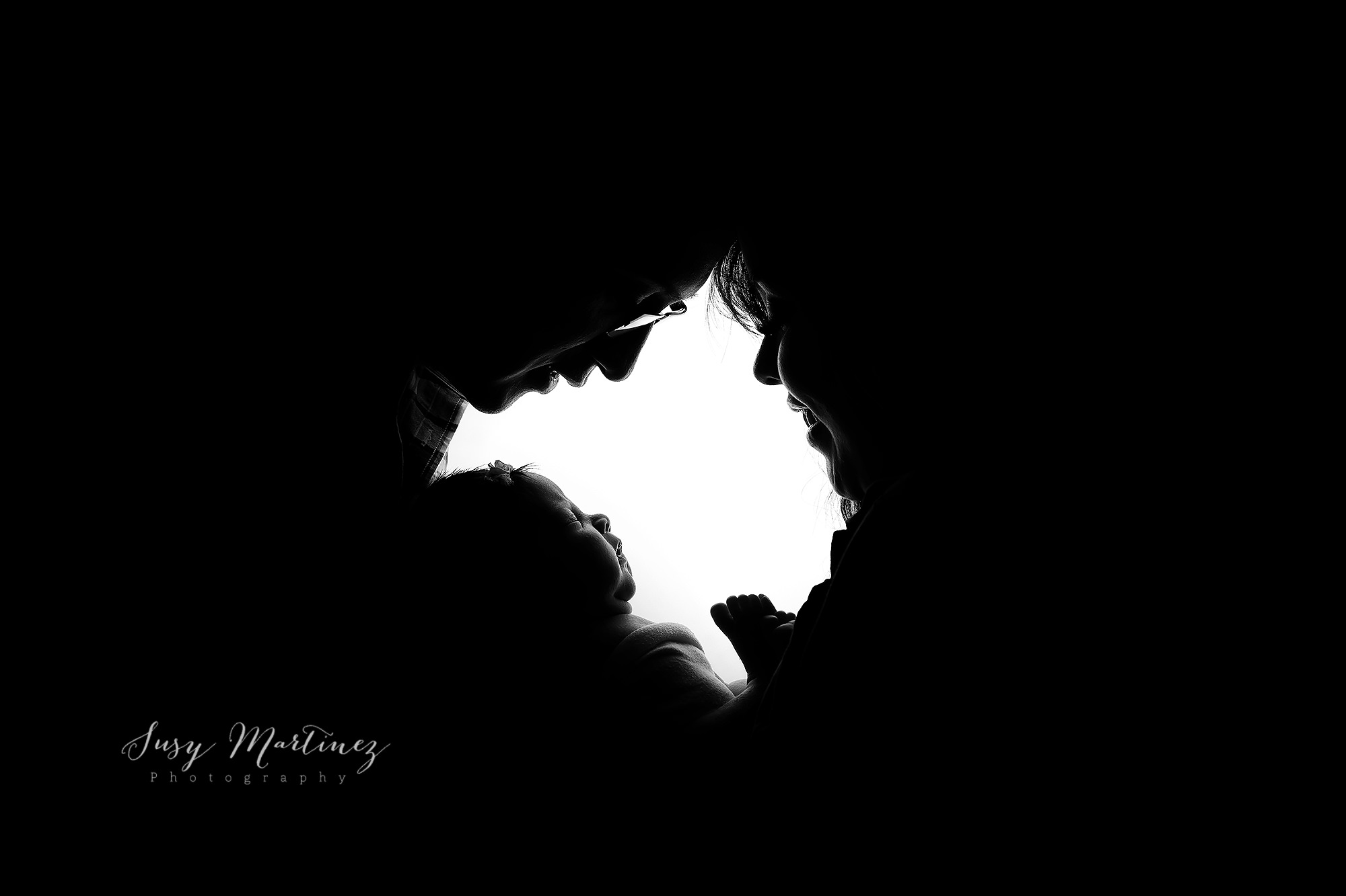 silhouettes of parents holding new baby girl