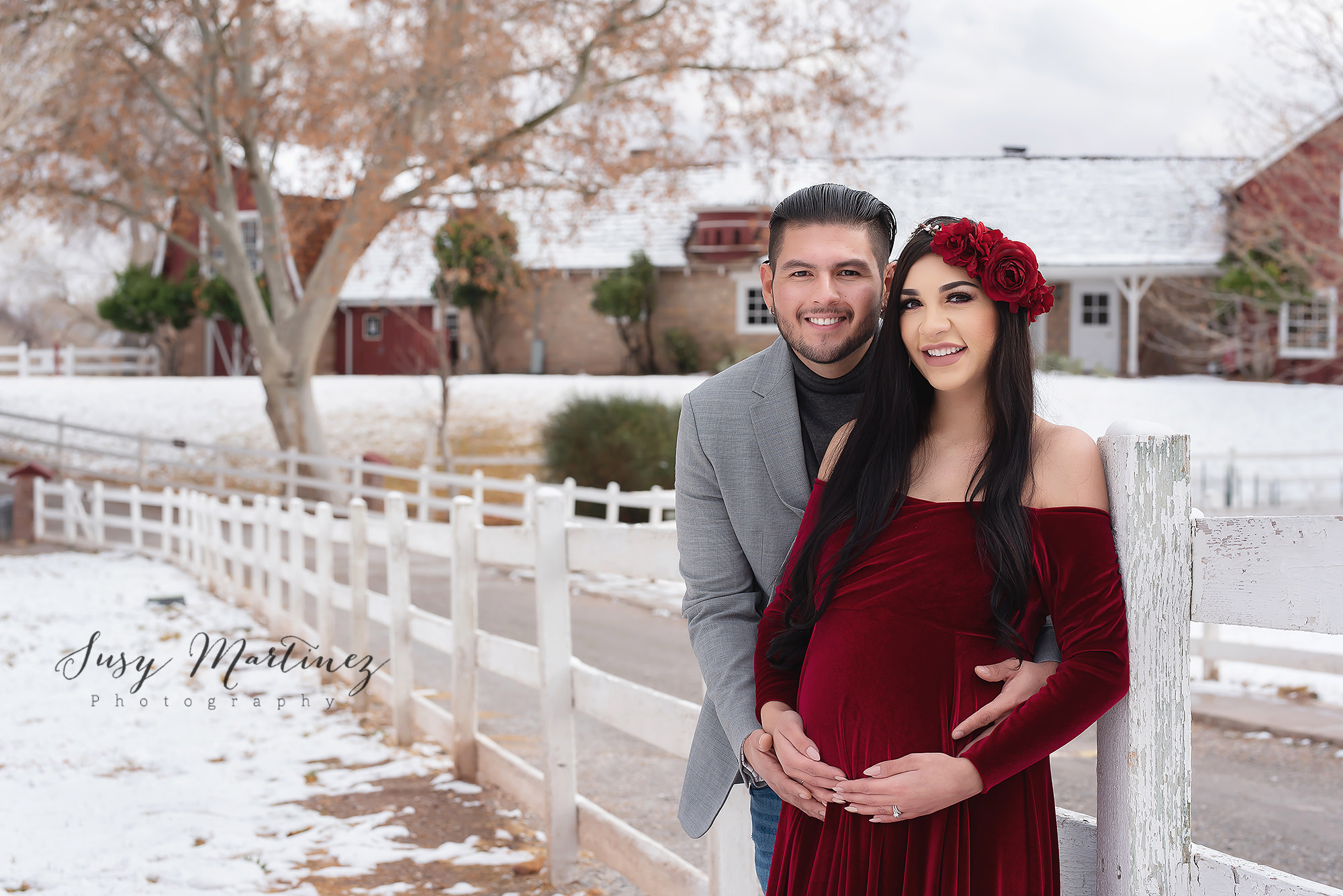 parents pose by fence at Spring Mountain Ranch during winter maternity photos
