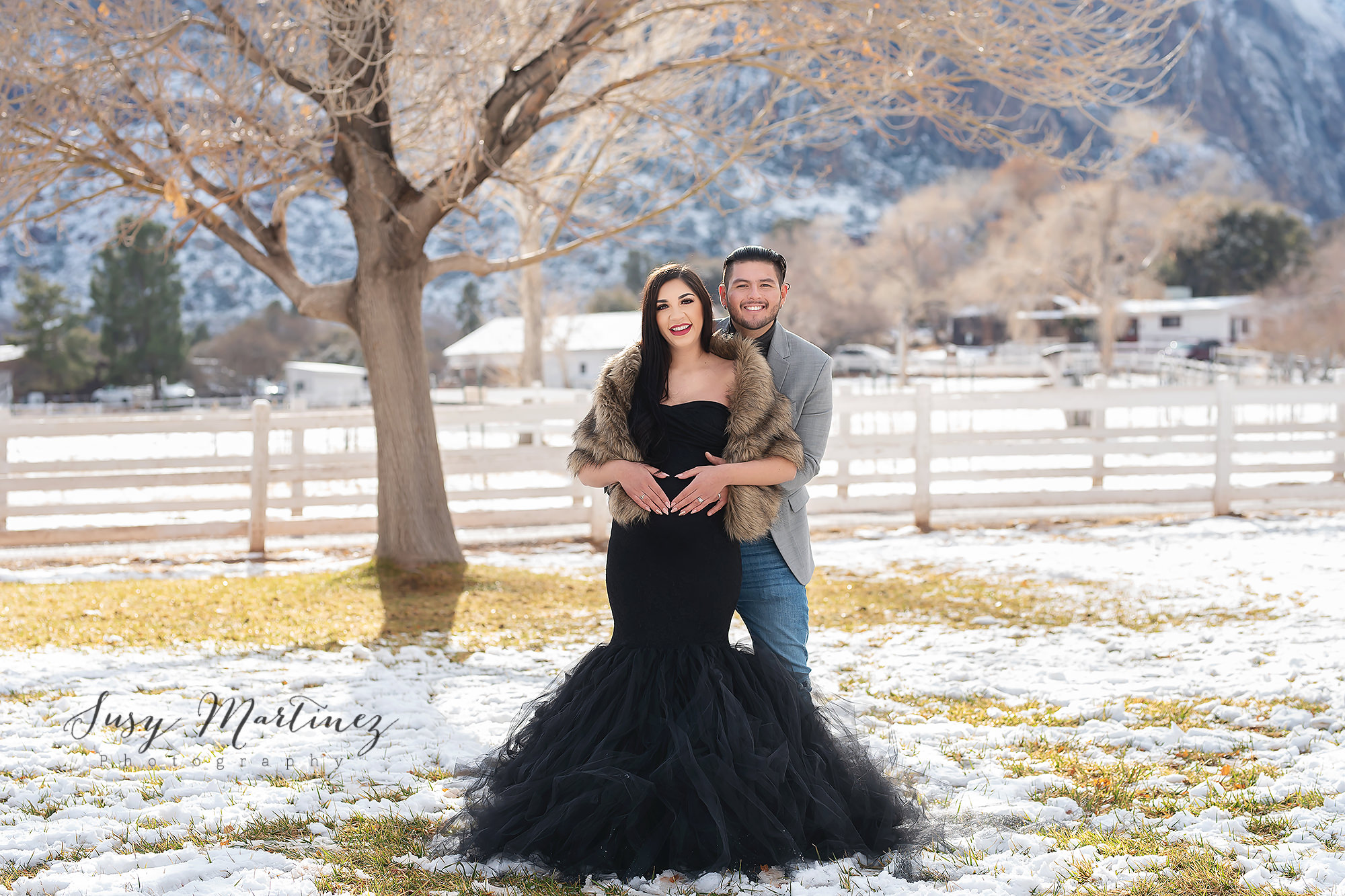 couple poses in the snow at Spring Mountain Ranch during winter maternity photos