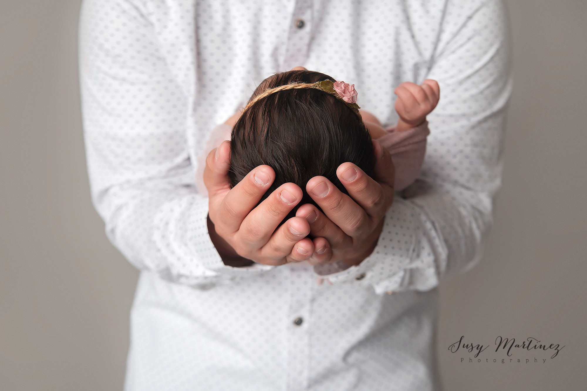 dad holds baby girl in his hands photographed by Susy Martinez Photography