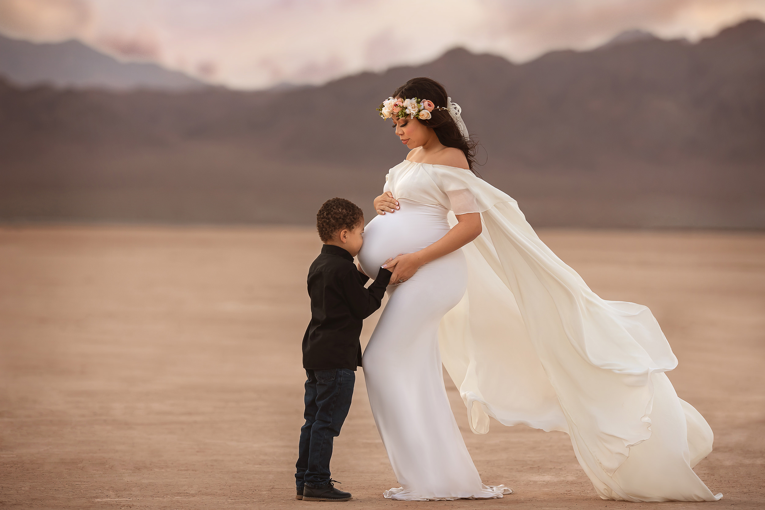 boy kisses mom's belly during maternity session in Dry Lake Bed