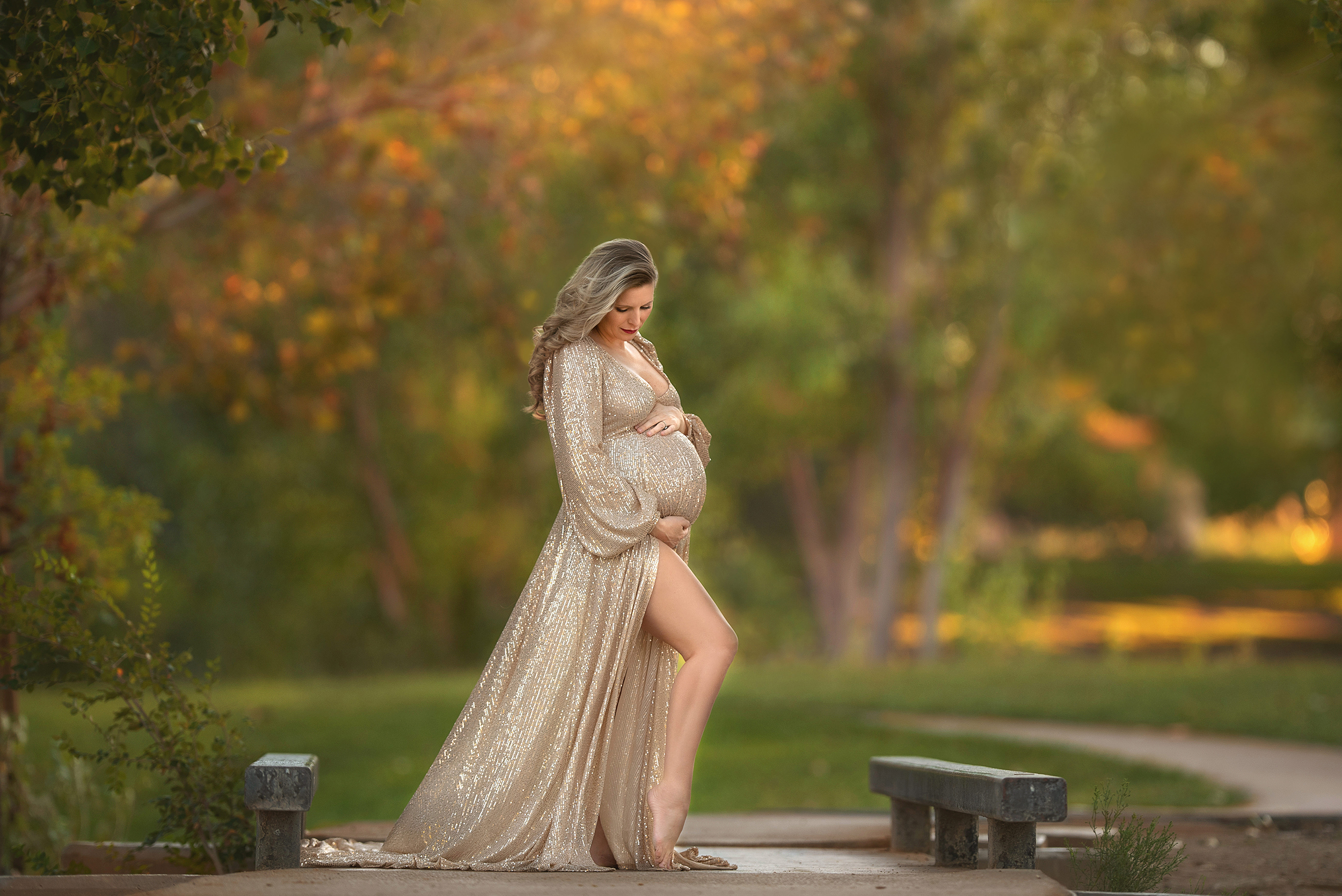 expecting mother stands holding baby bump in Sew Trendy Accessories gown at Floyd Lamb Park