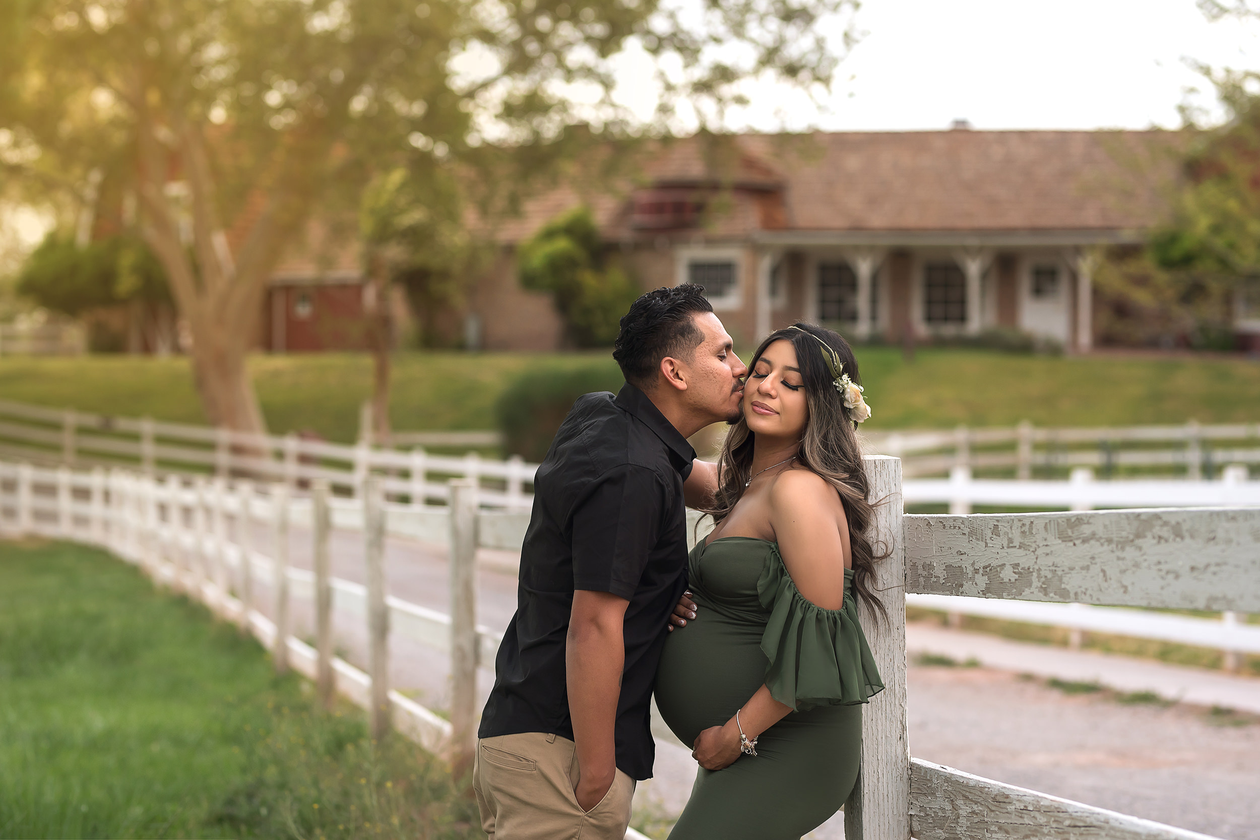 man kisses woman's cheek while she holds baby belly during Spring Mountain Ranch Maternity Session
