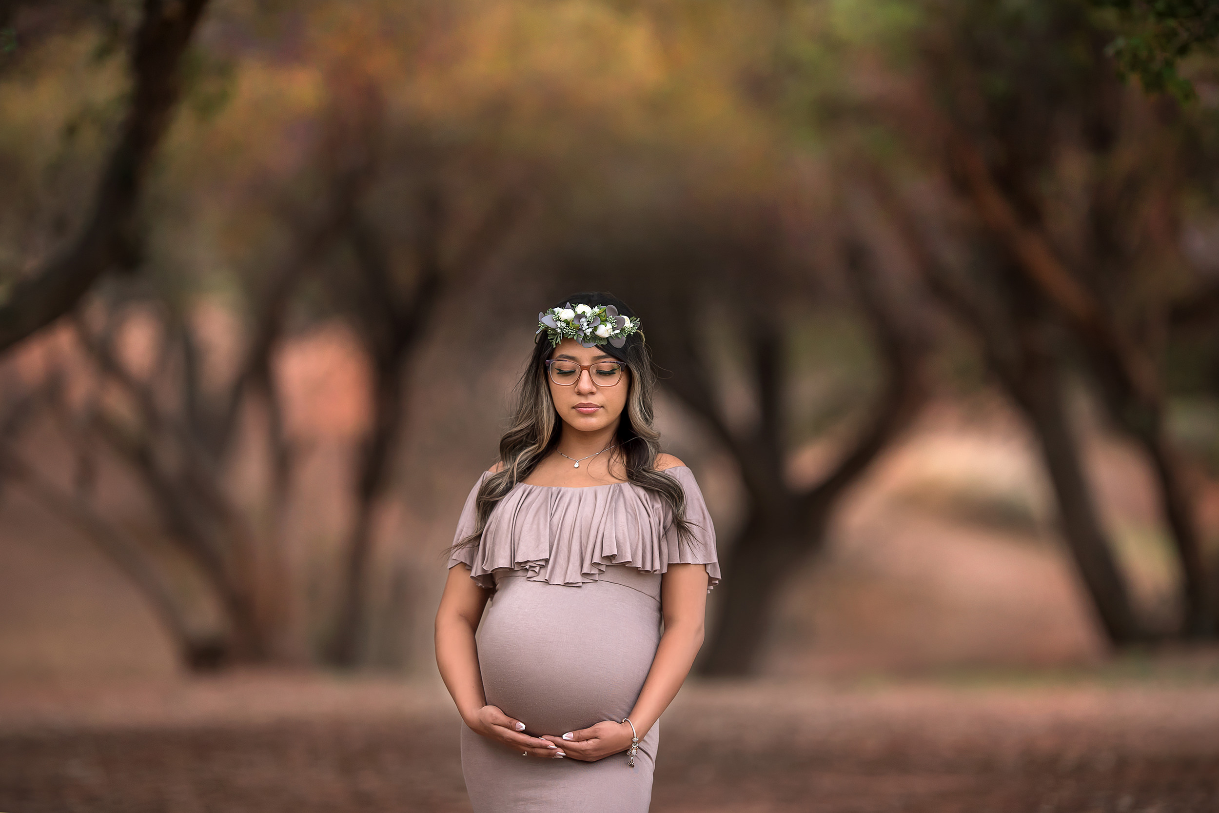 Las Vegas mother stands holding belly in mocha gown at Spring Mountain Ranch