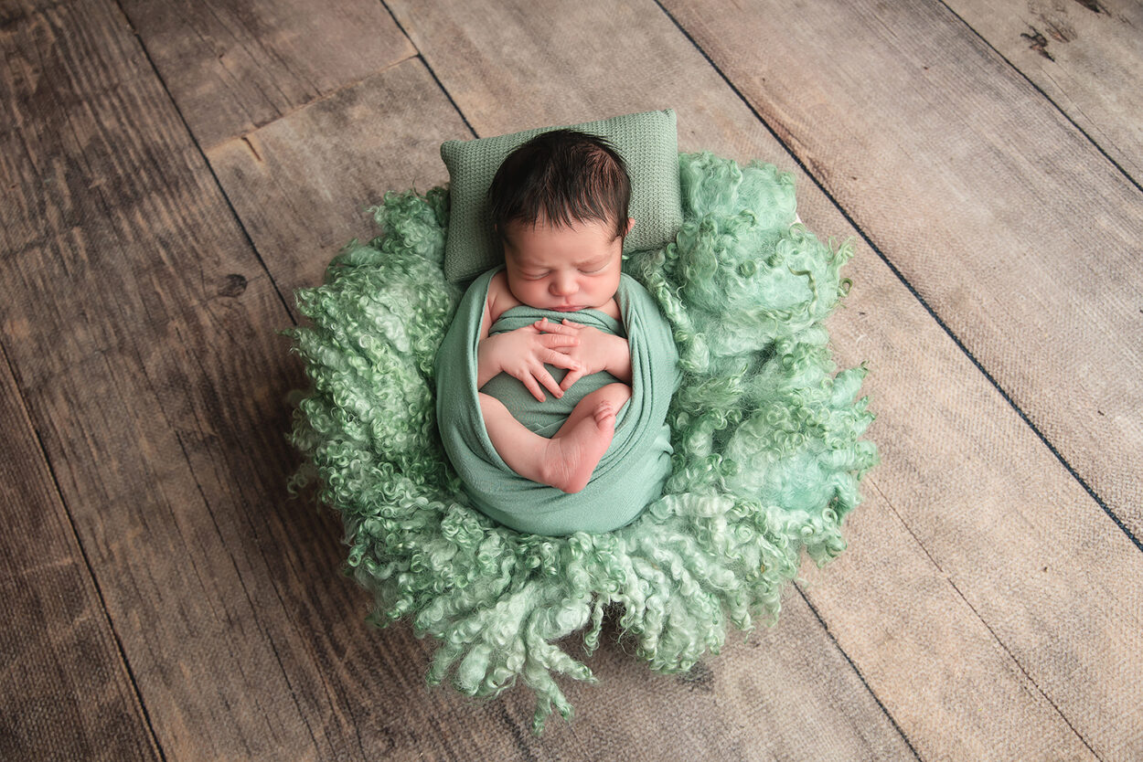 baby boy sleeps in green wrap on a wool layer with Las Vegas photographer 
